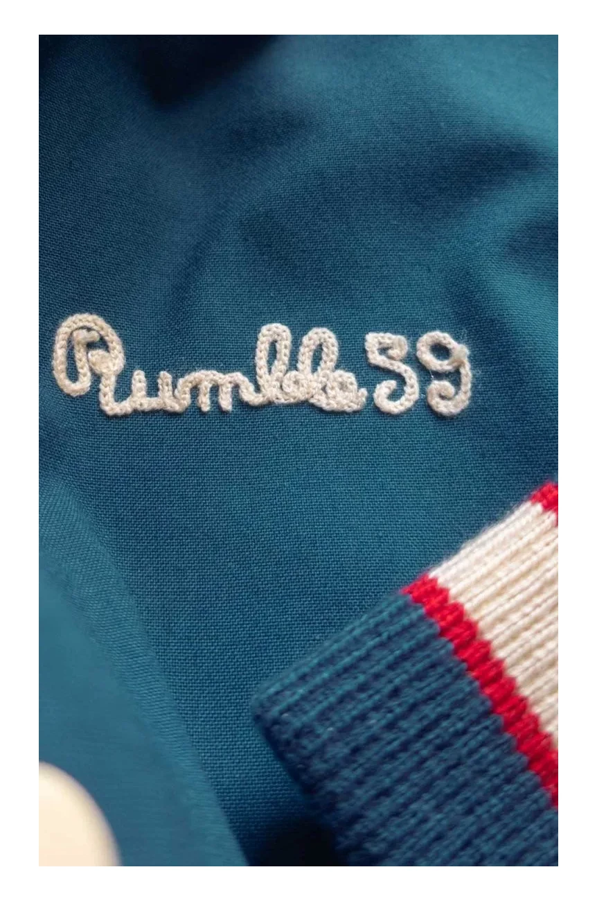 Détail broderie cursive Rumble59 sur veste bowling homme bleu pétrole, finition vintage authentique style années 50